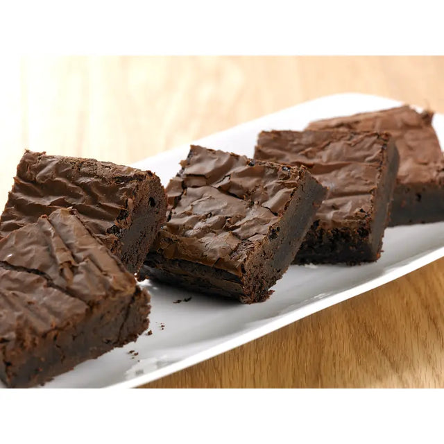 Rich fudgy chocolate brownie with a glossy cracked top on a white plate from brownie gf handmade cake co