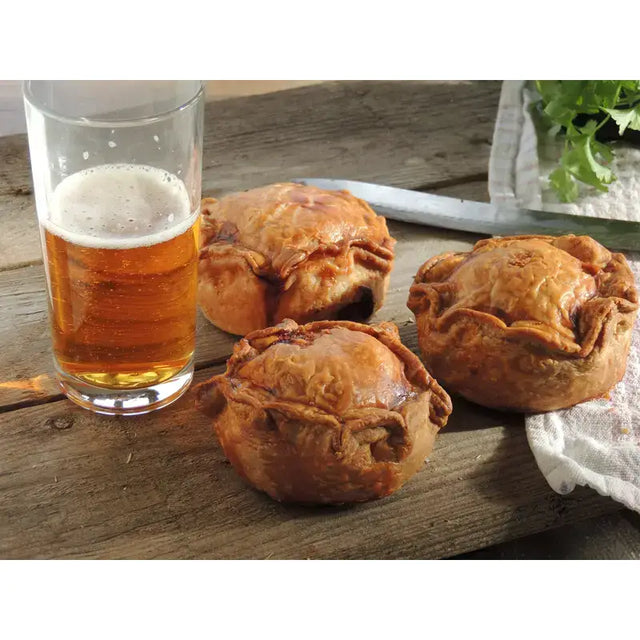 Golden-brown flaky chunk squealer pork pies with rustic hand-sewn edges on a wooden surface