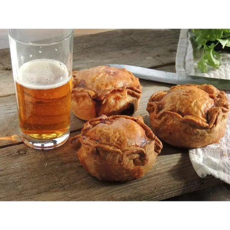 Golden-brown flaky chunk squealer pork pies with rustic hand-sewn edges on a wooden surface