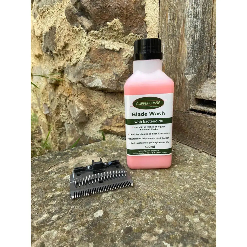 Pink liquid clippersharp blade wash in a white plastic bottle with black cap labeled with bactericide for blade care