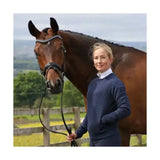 A dark brown horse wearing a black bridle with rhinestones next to a coldstream foulden sweater navy with technical raised hexagonal pattern
