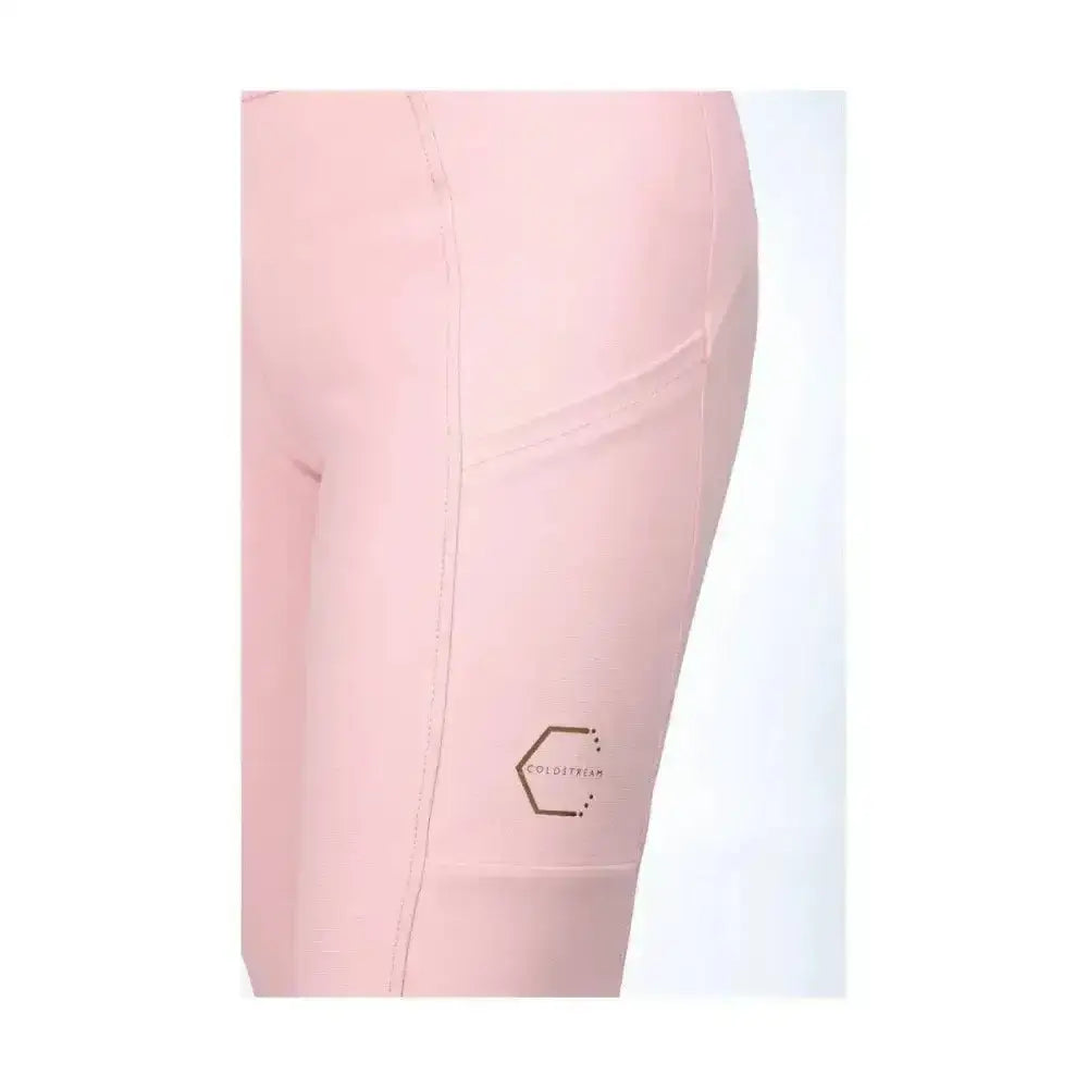 A pair of soft blush pink generation cranshaws riding tights with a subtle hexagonal logo near the thigh