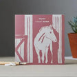 A pink and white colour block pony card featuring a horse in a barn with home sweet home text above it