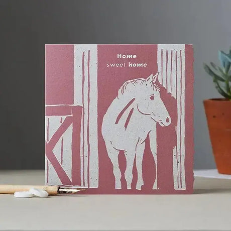 A pink and white colour block pony card featuring a horse in a barn with home sweet home text above it