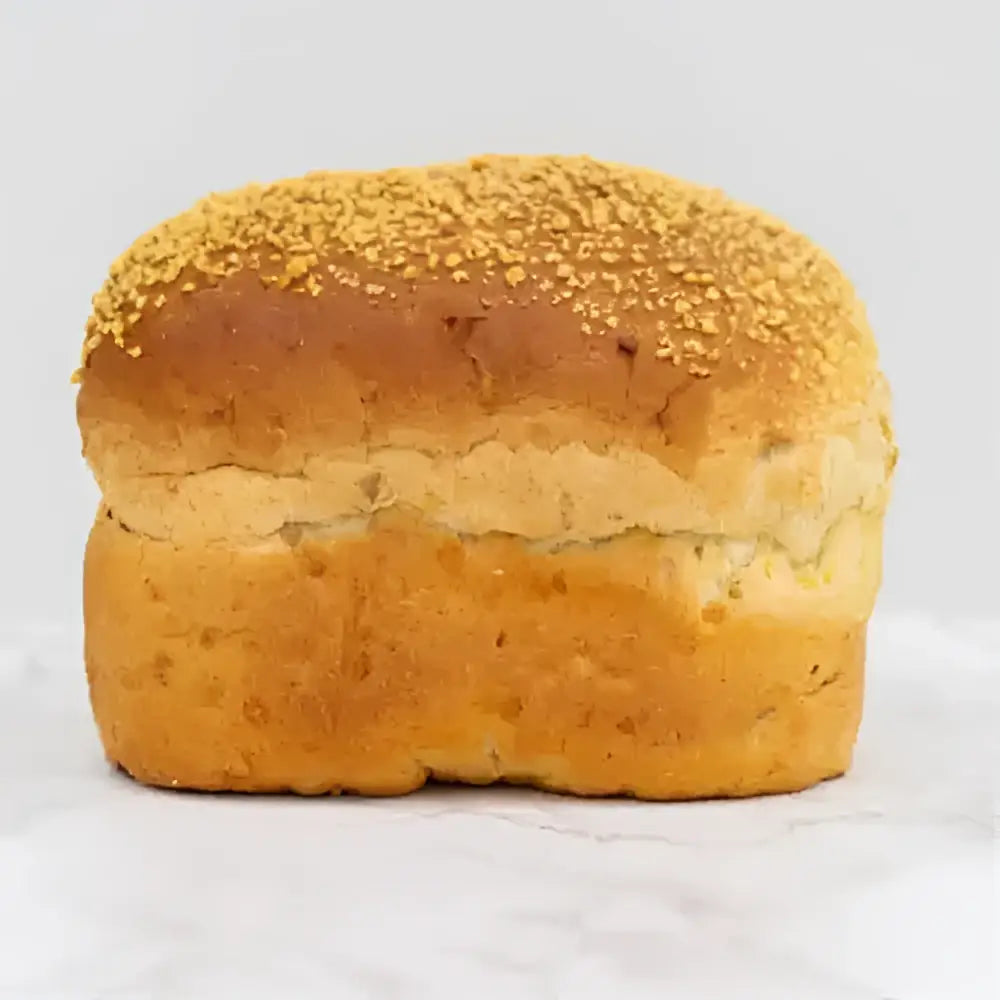 Golden-brown corn bread farmhouse loaf with sesame-seeded top and soft airy interior perfect as a round white bread