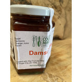 A glass jar of country markets damson jam with a white lid filled with dark reddish-purple preserve