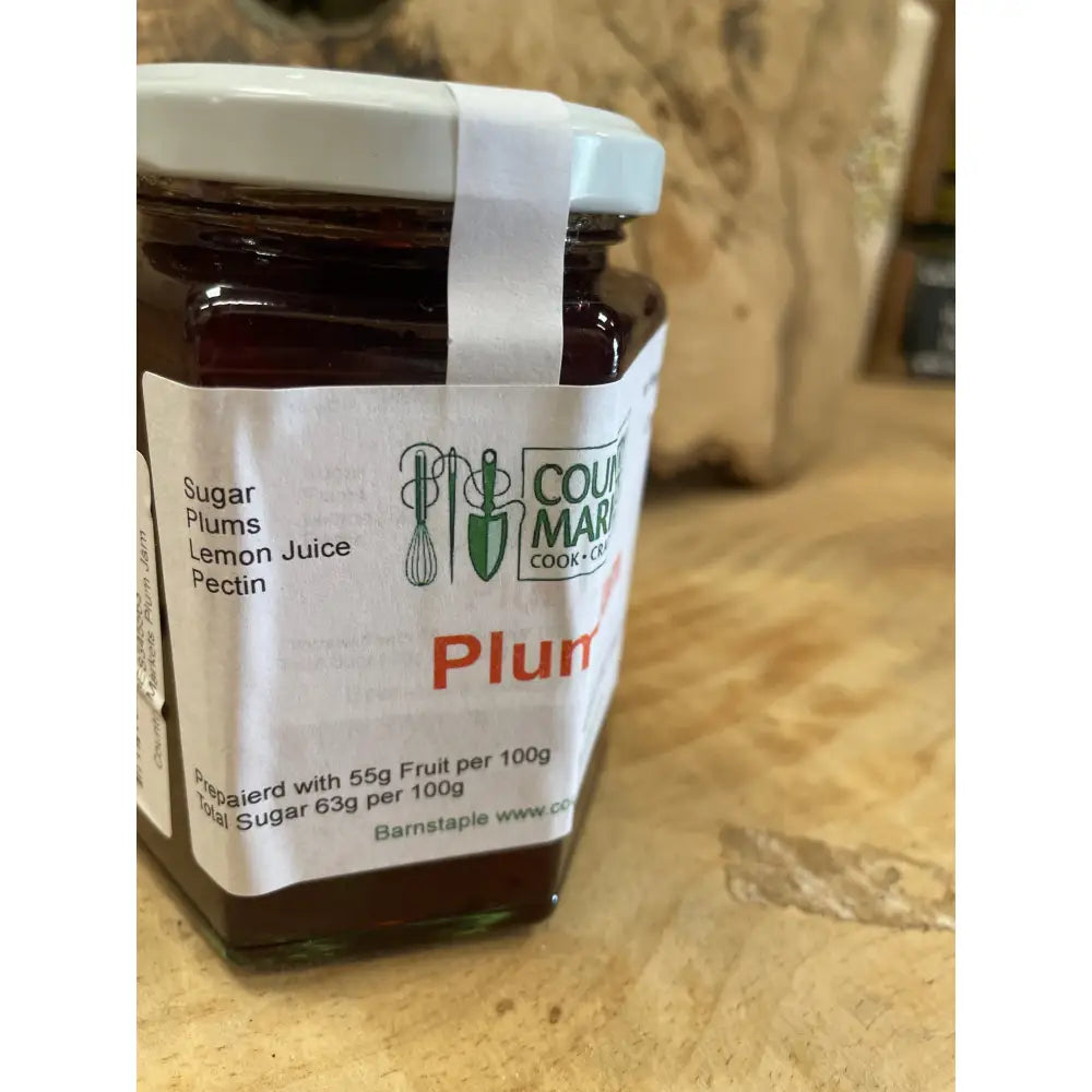 A glass jar of country markets plum jam with a white lid and label featuring the country market logo