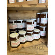 Hexagonal glass jars of country markets summer berry jam filled with amber marmalade and sealed with white lids