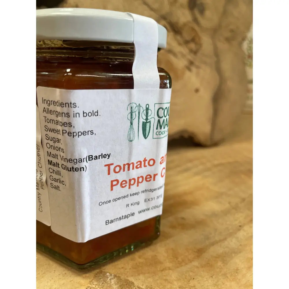 A glass jar of country markets roast pepper chutney with a white lid filled with rich amber tomato spread