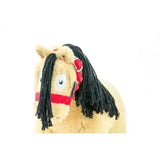 A plush tan horse toy with black yarn mane wearing a red harness from crafty ponies headcollars toy pony headcollars