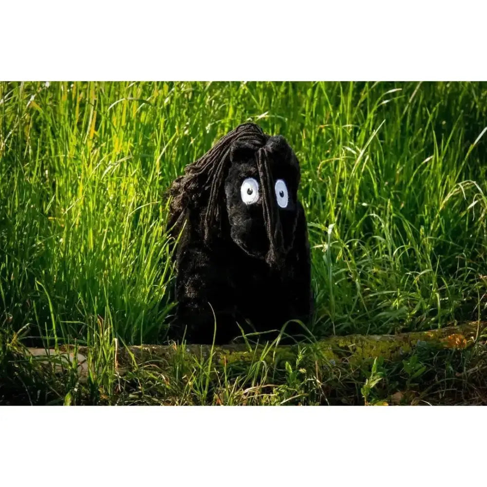 A crafty ponies soft toy pony all black with long dreadlocks and big white eyes peeking from tall green grass