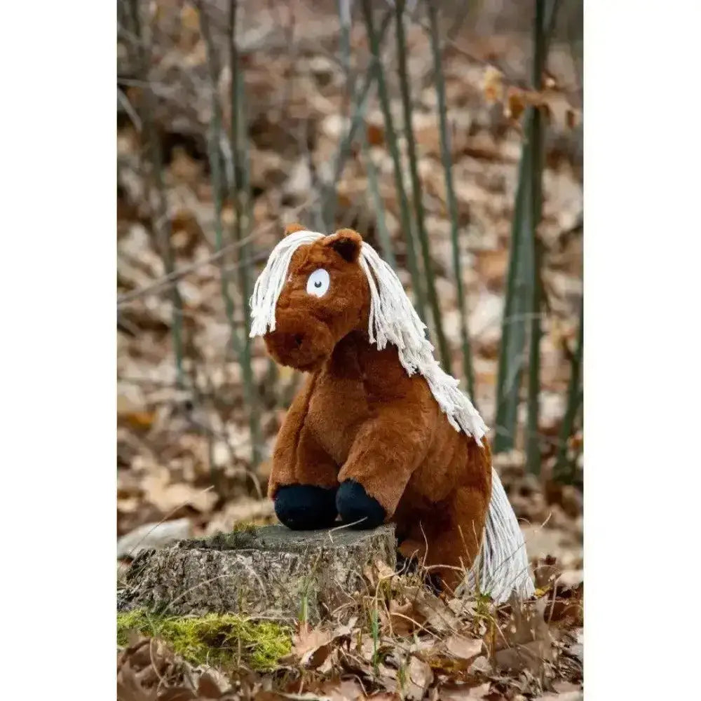 A crafty ponies soft toy pony brown with plush material and white mane sitting on a tree stump