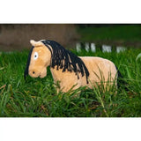A plush tan crafty ponies soft toy pony dun with black fringed mane and embroidered eyes sitting in green grass