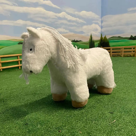 A crafty ponies soft toy pony white with a fluffy mane and tan hooves standing on artificial grass