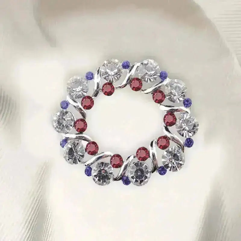 A circular crystal patriot stock pin with swirling silver design and clear red purple rhinestones perfect for blue patriotic stock look