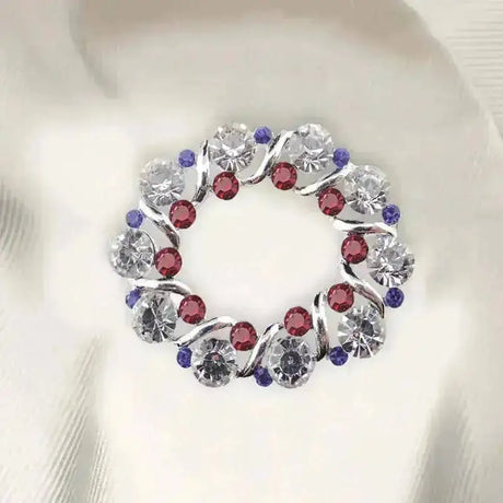 A circular crystal patriot stock pin with swirling silver design and clear red purple rhinestones perfect for blue patriotic stock look