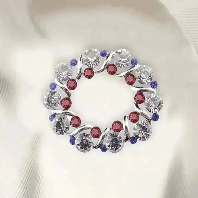 A circular crystal patriot stock pin with swirling silver design and clear red purple rhinestones perfect for blue patriotic stock look