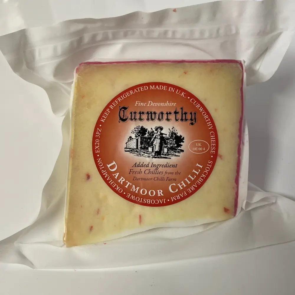 A square block of pale yellow curworthy cheese dartmoor with red chilli speckles wrapped in white plastic bag