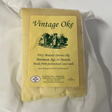 A block of pale yellow aged curworthy cheese devon oke wrapped in clear plastic with a vintage label vintage oke