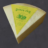 A wedge of creamy yellow curworthy cheese devon with a bright yellow label featuring green text and illustrations