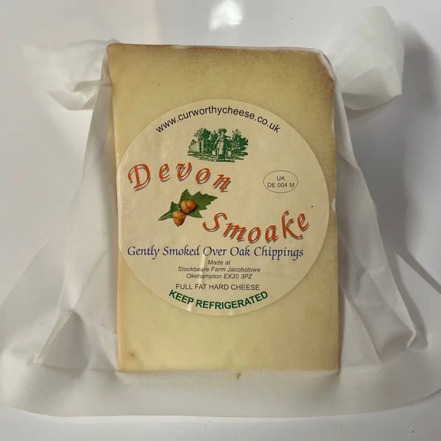 A rectangular block of pale yellow curworthy cheese devon smoake wrapped in clear plastic features natural oak flavor