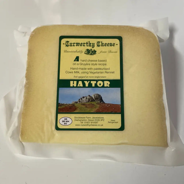 A block of pale yellow curworthy cheese haytor wrapped in clear plastic with a green and cream label showing haytor rock formation