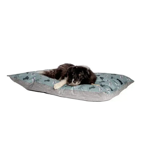A soft light blue deep duvet dog bed with dark green dinosaur prints and striped sides from danish design battersea playful dogs