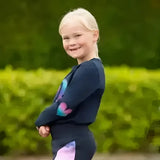 A young girl wearing a dazzling night long sleeve navy t-shirt with colorful heart designs on the sleeves by little rider