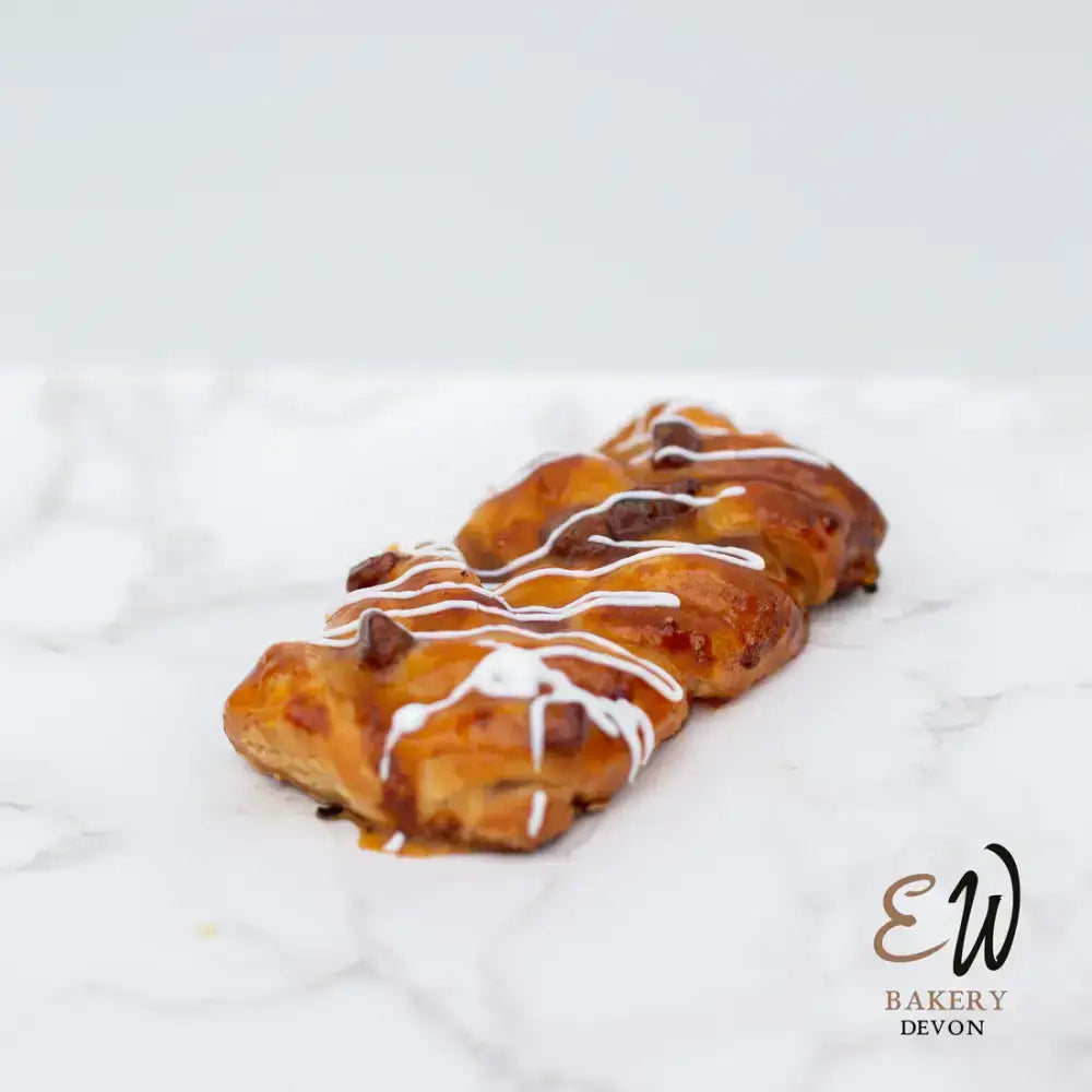 Golden-brown west danish pastry braided with chocolate chips and white icing drizzle, not a round white bread