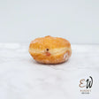 A golden-brown sugar-dusted jelly-filled round white bread from east and west doughnuts with a soft glossy exterior