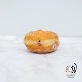 A golden-brown sugar-dusted jelly-filled round white bread from east and west doughnuts with a soft glossy exterior