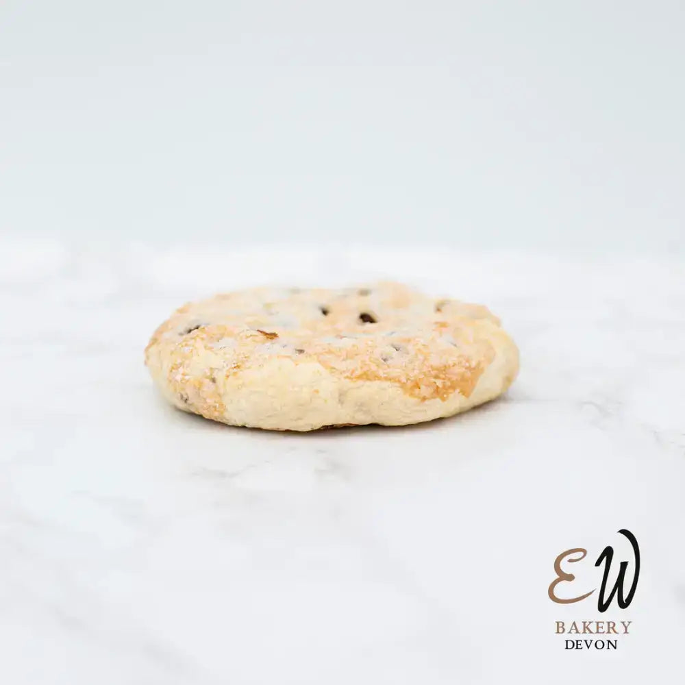 A golden-brown east & west eccles cake shortbread cookie with dark chocolate chips, not round white bread style