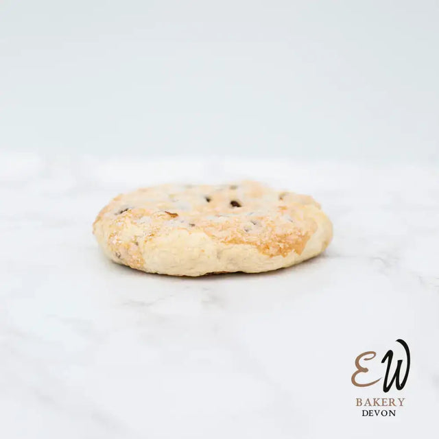 A golden-brown east & west eccles cake shortbread cookie with dark chocolate chips, not round white bread style