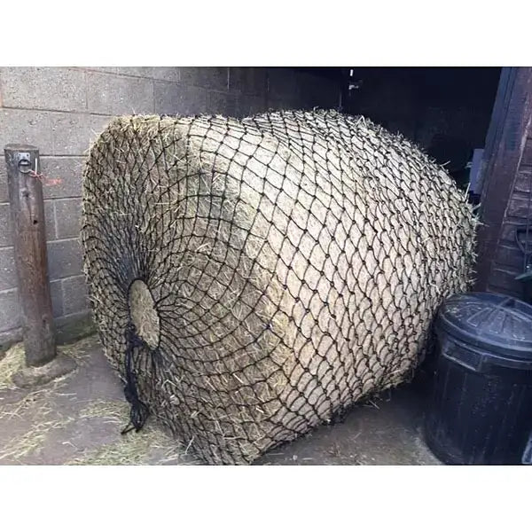 A large round elico wild boar bale haynet wrapped in black mesh with strong tying cord for secure hay storage