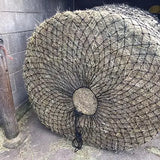 A round bale of hay wrapped in black mesh using elico wild boar x-large boar bale haynet with strong tying cord