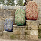 Three colorful netted hay bales stacked on stone steps featuring elim-a-net blue haynet forage regulation mesh haylage extra strong design