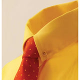 A vibrant red tie with white polka dots neatly knotted showing equetech collar pin against yellow shirt