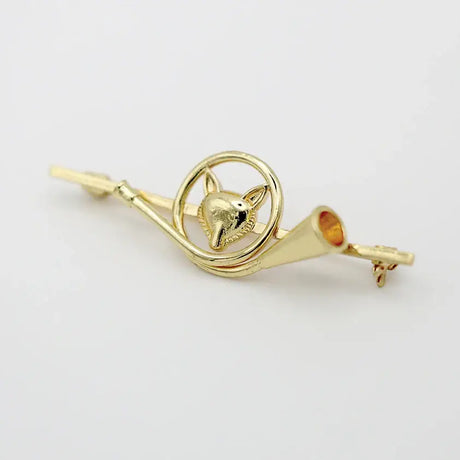 Gold-colored metal equetech french horn fox stock pin shaped like a fox head with decorative horn elements encircled by a ring