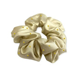 A cream-colored satin equetech hair scrunchie with small yellow beads accented jacquard hair accessory pin spot