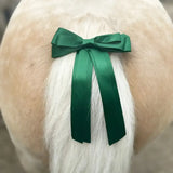 A vibrant emerald green satin equetech horse competition warning tail ribbon tied neatly on a fluffy white dog tail