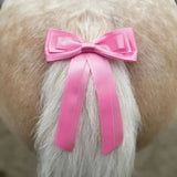 A vibrant pink satin equetech horse competition warning tail ribbon tied neatly around a dog tail