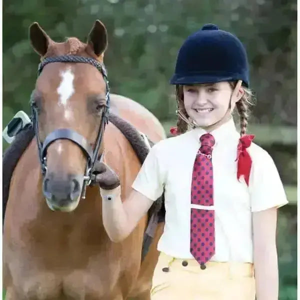 A young girl wearing a white equetech junior waffle showing shirt with advanced fabric technology and yellow riding pants