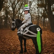 A black horse wearing equetech mummy mayhem horse gear with white bandages and a bright green horse tail tassel