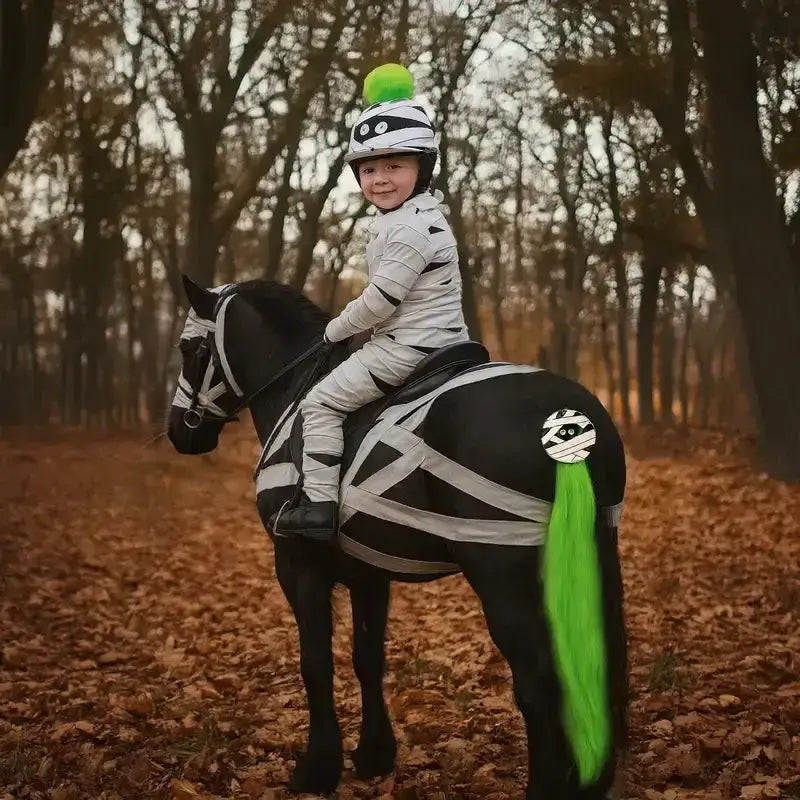 A black horse wearing equetech mummy mayhem horse gear with white bandages and a bright green horse tail tassel