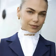 Gold-toned sparkling equetech ready-tied stock rose gold crystal brooch pinned at the collar of a white shirt