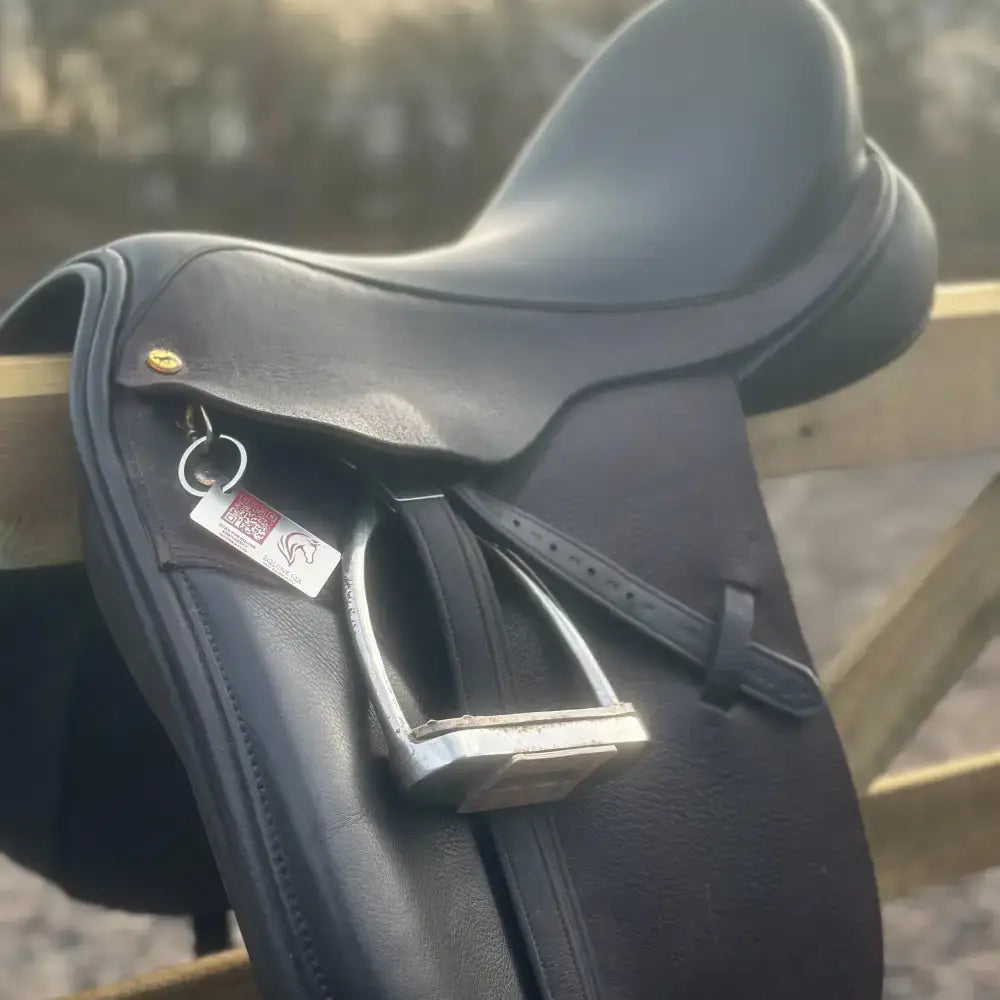Black leather english saddle with silver stirrups and gold buckle next to equine emergency tag for instantly accessible emergency contact details
