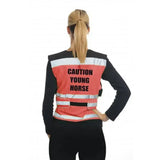Bright orange equisafety air waistcoat caution with reflective stripes and young horse pink text worn over black shirt