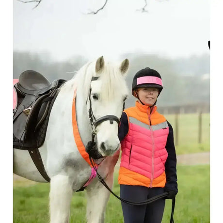 White horse wearing black saddle and orange halter with equisafety hi-vis riding gilet pink for safety riding