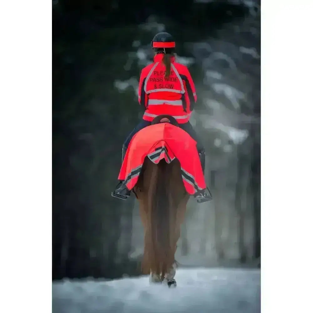 Rider wearing a bright red high-visibility winter exercise rug with reflective stripes and performance fabric wraparound design