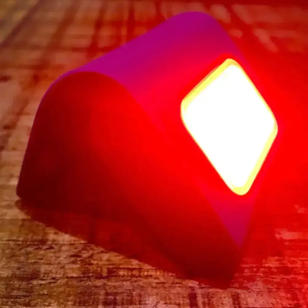 A glowing red and purple equisafety led strong rechargeable magnetic light with a bright white square led panel